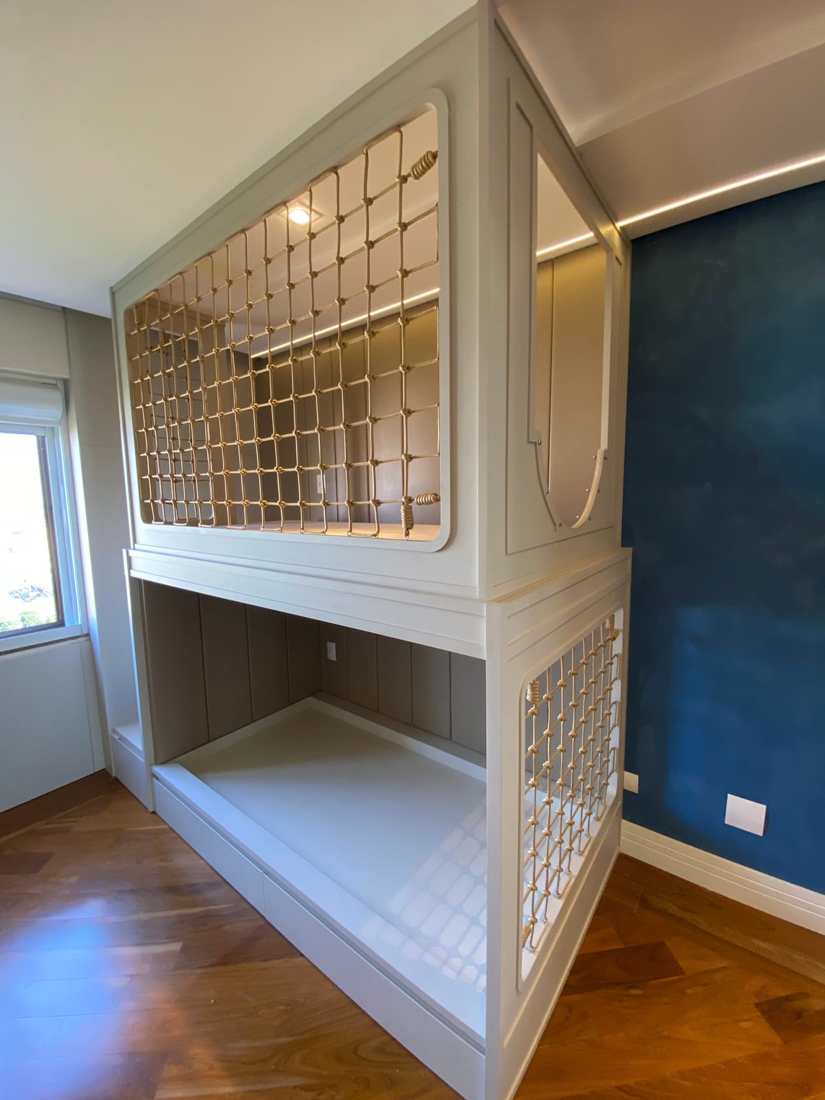 Cama cabana branca com trama quadrada de macramê na cama de cima e na de baixo, parede azul